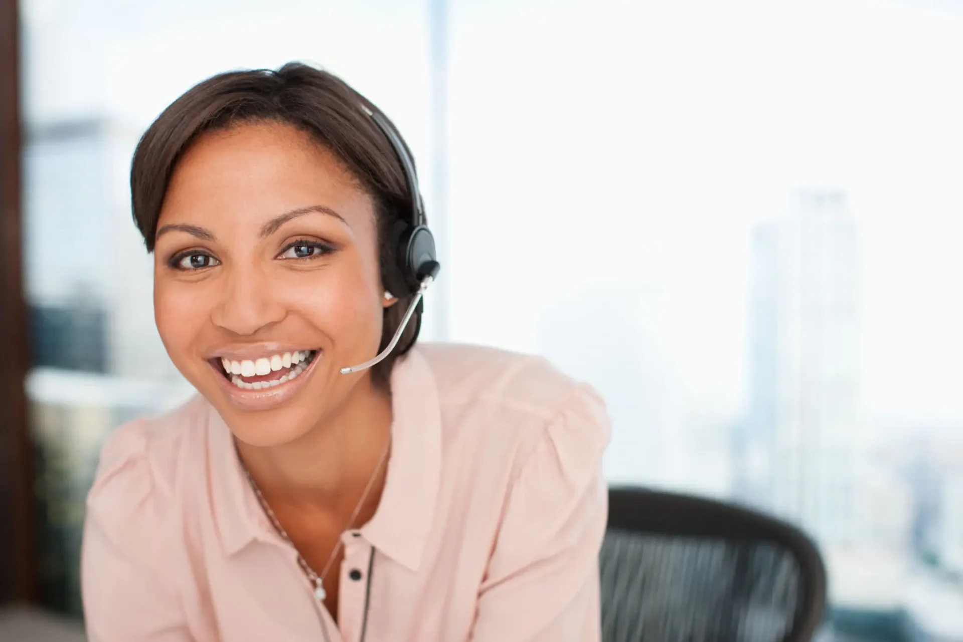 Smiling woman wearing a headset at a desk.