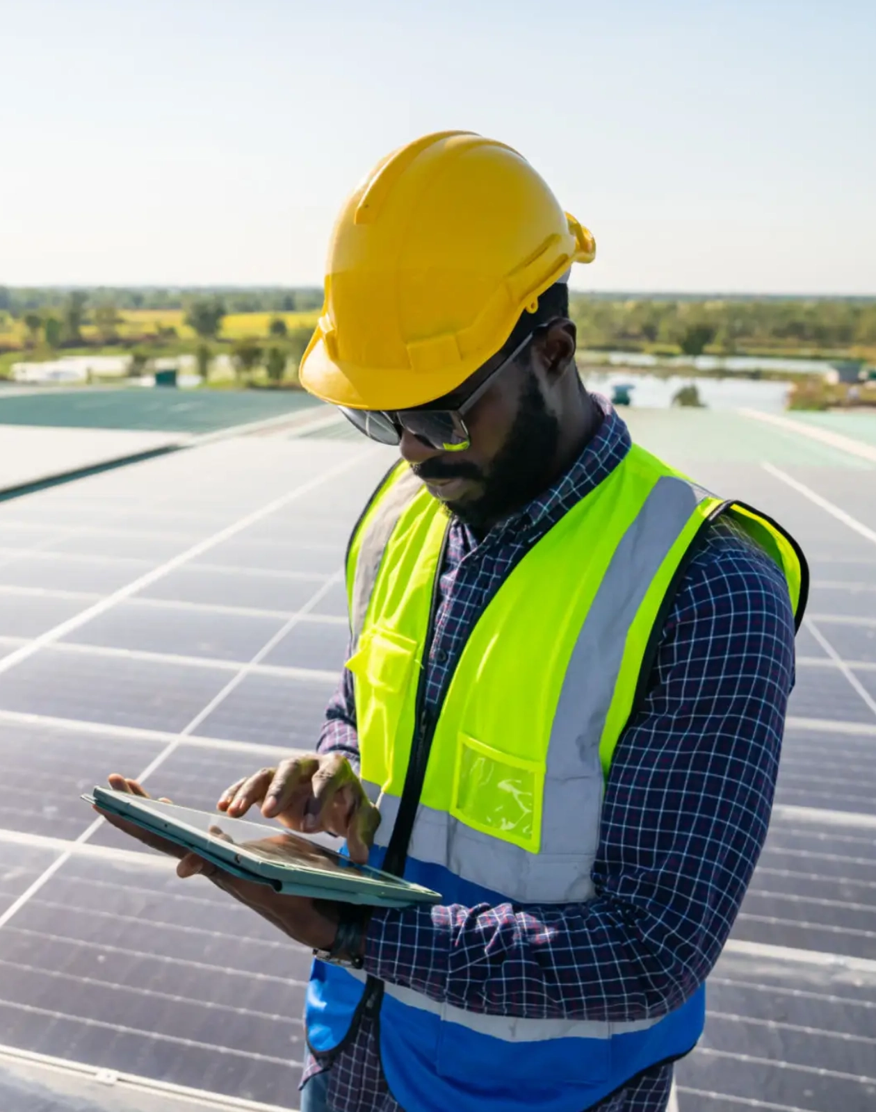Engineer inspecting solar panels outdoors, wearing safety gear.