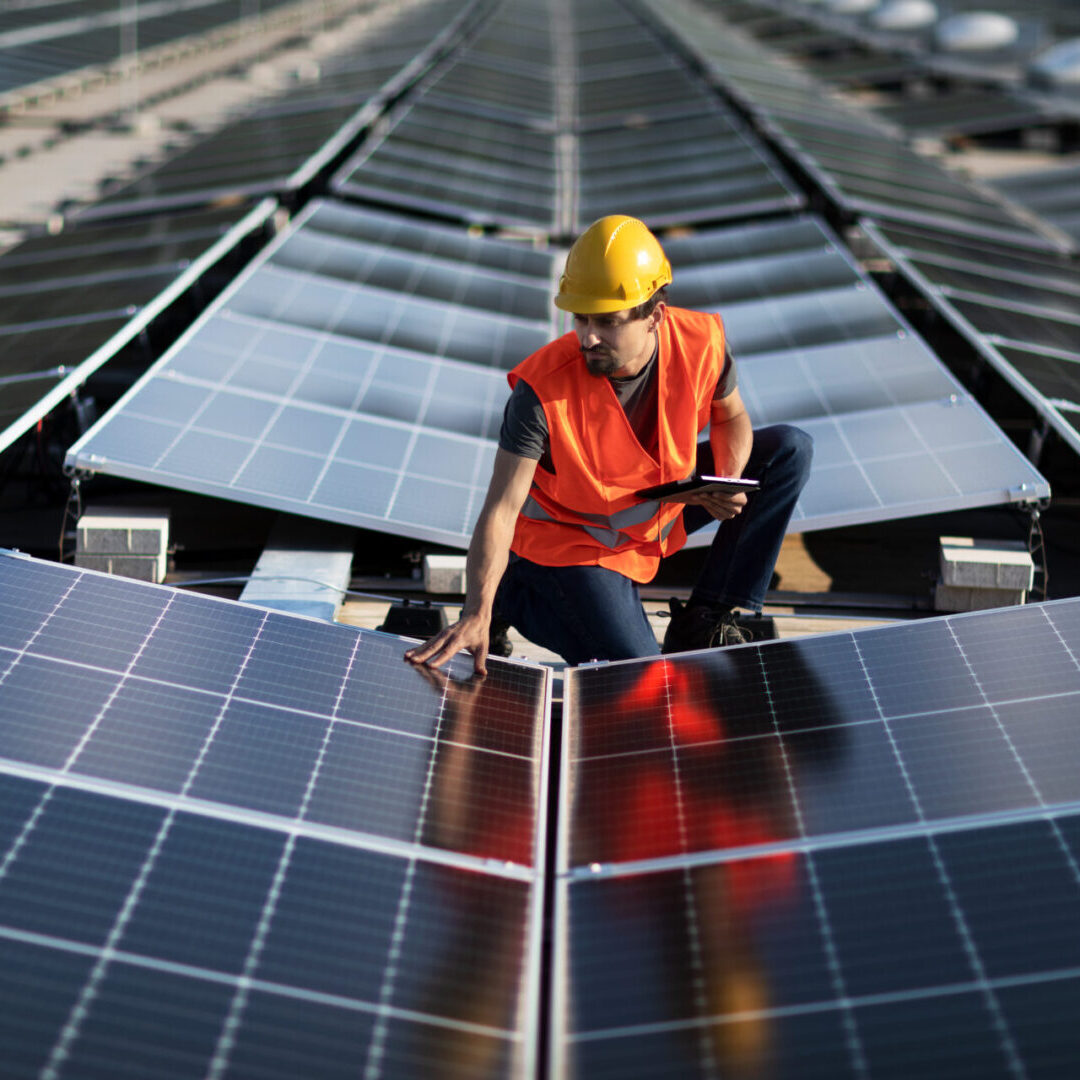 Worker inspecting solar panels on a rooftop installation.